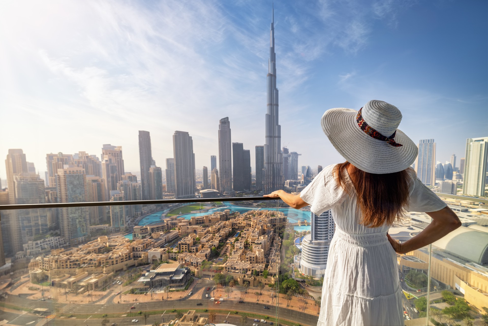 A elegant woman in a white dress looks at the view of the downtown skyline of Dubai